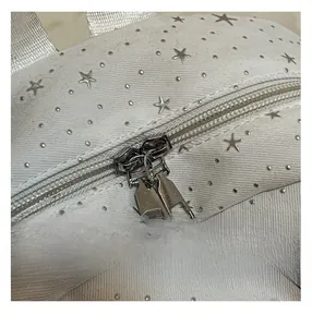 Macro shot of minimalist white backpack with silver star studs and dual metal zippers