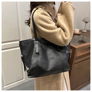 Detail of black faux leather tote bag with silver star rivets on the shoulder strap