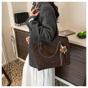 Detail of vintage brown tote bag with white stitching and bear charm on shoulder