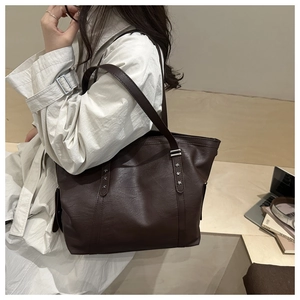 Detail of dark brown tote bag featuring lychee texture and silver star rivet accents