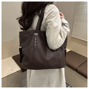 Detail of deep brown tote bag featuring decorative silver star studs on the shoulder strap