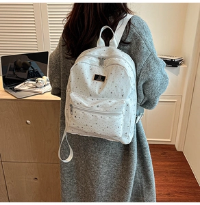 White mini backpack with star pattern shown on model in a cozy study setting