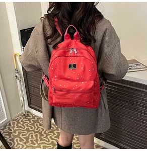 Detail of a red canvas backpack with white star patterns and sturdy metal zippers