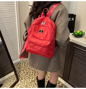 Red canvas backpack with silver star print shown in a casual lifestyle setting