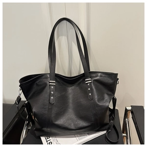 Close-up of black leather tote bag featuring star studs and silver metallic buckles
