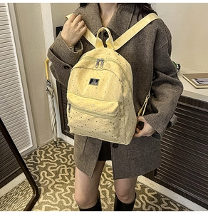 Detail of yellow backpack with silver star pattern and premium metal zipper on model