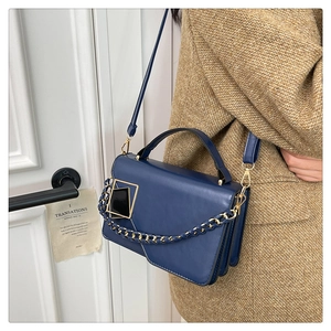 Dettaglio della borsa blu in pelle con fibbia dorata su un cappotto di lana