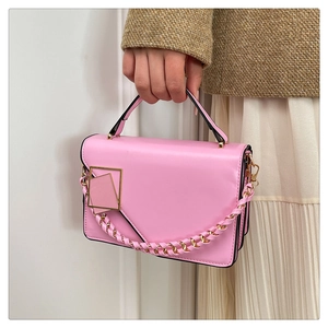 Dettaglio borsa in pelle rosa con fibbia geometrica dorata e tracolla intrecciata