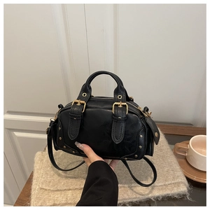 Detail view of a vintage black PU leather bag with gold buckles and metallic rivets