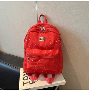 Detail view of red backpack with white star pattern and metallic JUHAI logo plaque