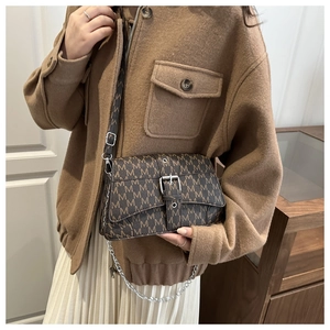 Close-up of brown crossbody bag featuring 'M' print, metal buckle and chain detail