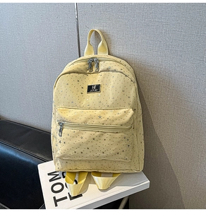 Detail of yellow canvas backpack showing silver star prints and metal zipper texture
