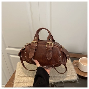 Detailed view of a brown vintage leather handbag with rivet decor and metal buckle straps