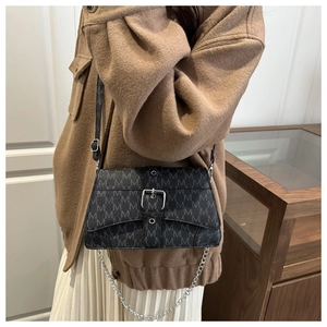 Detail of a black crossbody bag with M-letter print, silver buckle, and chain strap