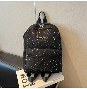 Detailed view of black canvas backpack with star pattern and front zipper pocket