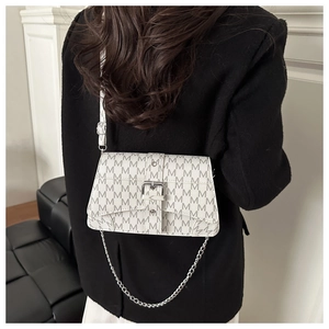Detail of white crossbody bag with M-pattern print and stylish silver chain accessory