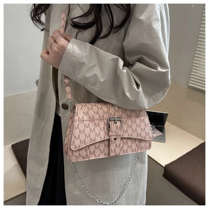 Close-up of pink crossbody bag with M print and silver chain strap on model shoulder