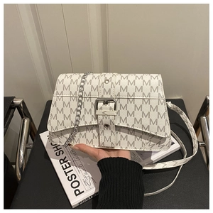 Close-up of white M-pattern crossbody bag with silver chain on leather chair