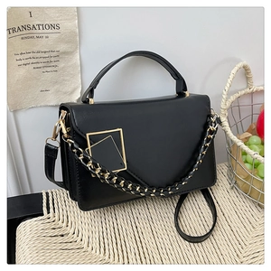 Dettaglio della borsa in pelle PU nera con fibbia dorata e catena decorativa intrecciata