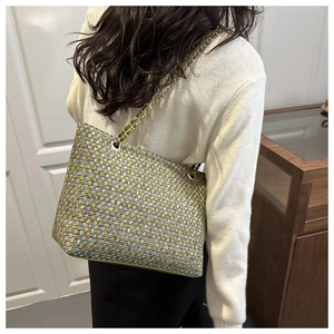 Detail of colorful woven shoulder bag featuring pastel tones and golden chain strap