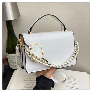 Elegante borsa bianca con fibbia dorata e catena intrecciata su uno sfondo lifestyle