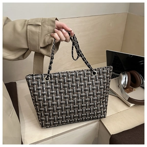 Detail van de tweed ruitjes tas met leren goudkleurige kettingriemen en geweven stof