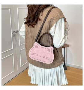 Détail du sac chat rose avec visage brodé et bandoulière marron porté par un modèle