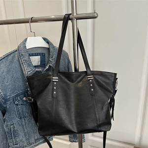 Large black faux leather tote bag with silver star studs and minimalist shoulder straps