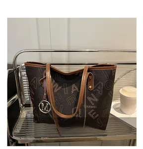 Detail view of large monogram tote bag with gold metal pendant and leather handles