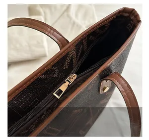 Detail of smooth golden metal zipper and vintage monogram texture on brown tote bag
