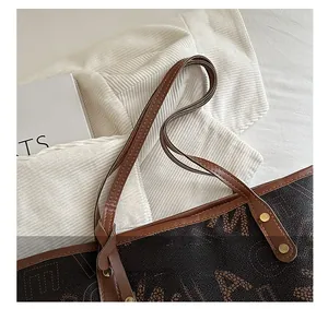 Detail of printed tote bag showing leather handle stitching and metal rivet craftsmanship
