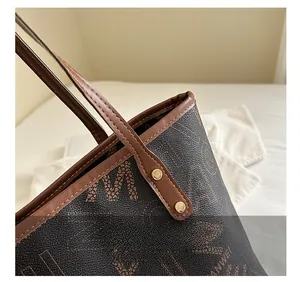 Detail shot of brown leather tote bag with logo print and golden rivet stitching