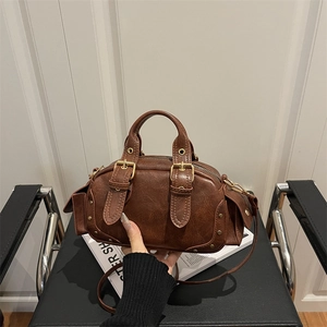 Vintage brown leather Boston bag with decorative buckles on a minimalist background