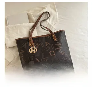 Detail view of printed tote bag with metal M charm and retro letter patterns