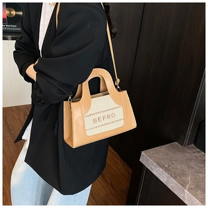 Détail du sac cabas en cuir marron clair et toile beige avec poignée et bandoulière