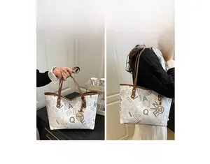 Detail of printed tote bag featuring brown leather handles and gold M-letter pendant