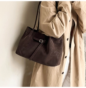 Dettaglio della borsa tote in pelle scamosciata marrone con fibbia su un trench beige