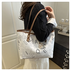 Detailed view of large tote bag with black letter print and brown leather trim details