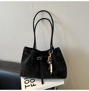 Dettaglio borsa tote in pelle scamosciata nera con ciondolo di perline e finiture in metallo