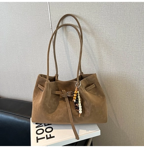 Dettaglio della borsa tote in pelle scamosciata marrone con ciondolo e fibbia in metallo