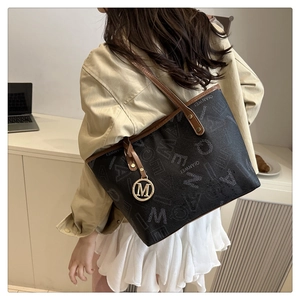 Detailed view of black tote bag with white lettering and brown leather straps