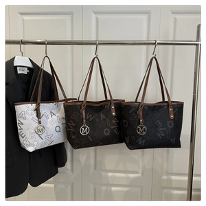 Detailed display of three patterned tote bags in white, brown and black with metal M charms
