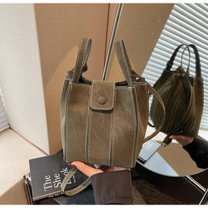 Close-up of retro dark green bucket bag with white contrast stitching and logo