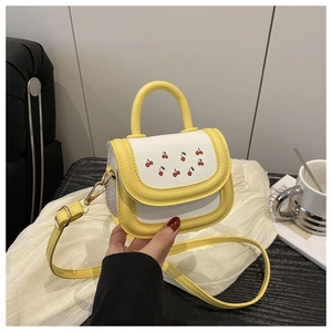 Detail of mini white crossbody bag with red cherry prints and bright yellow trim