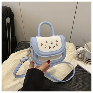 Detail of light blue and white leather mini crossbody bag with cute red cherry print design