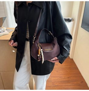Dettaglio della borsa hobo marrone scuro con trama scamosciata e ciondolo con perline