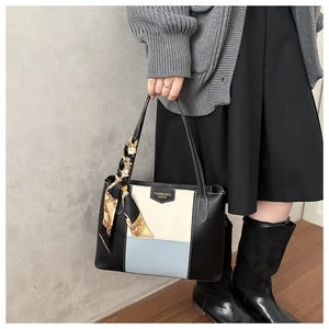Detail van de kleurblok tote tas met leren label en decoratieve zijden sjaal om handvat