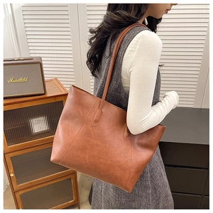 Close-up of brown vintage PU leather tote bag with long straps worn on shoulder