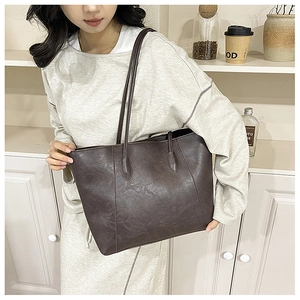 Close-up of a large vintage dark brown tote bag worn on a shoulder for daily commute
