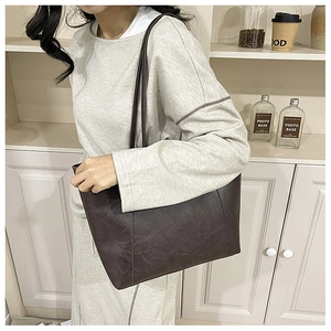 Close-up of a vintage brown leather tote bag with fine stitching and slim shoulder strap